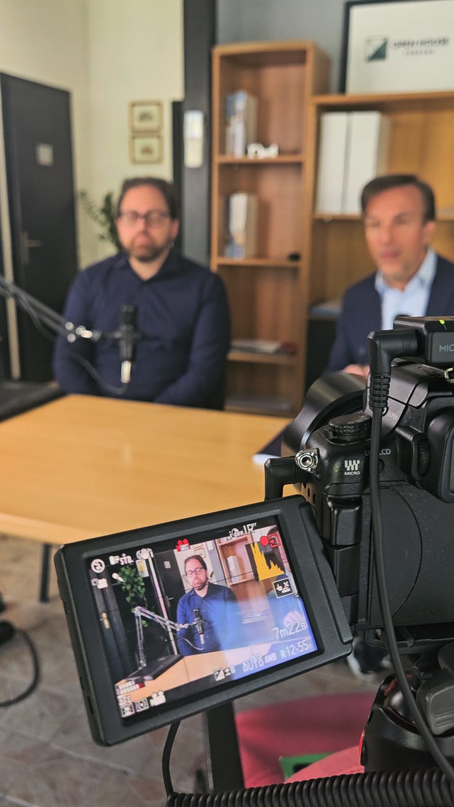 Monitor della camera durante la registrazione di un video podcast con due ospiti al microfono