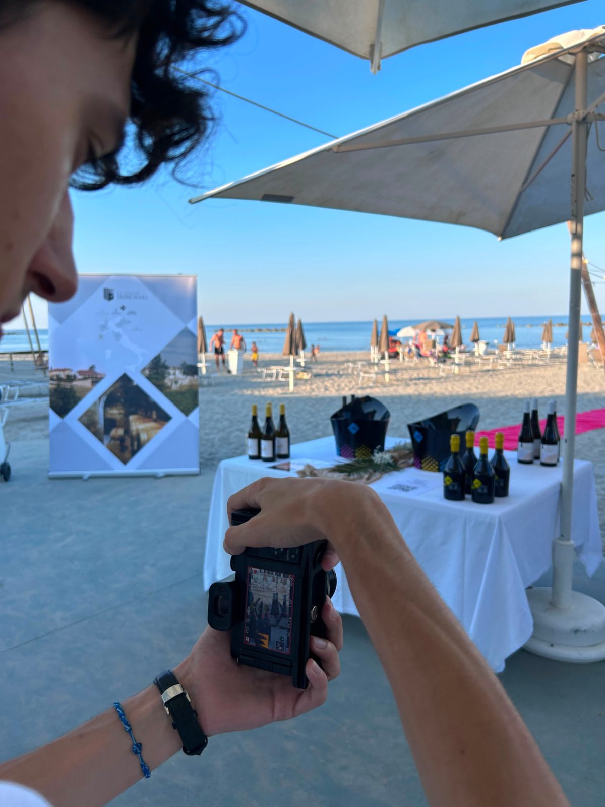 Riprese di un evento di degustazione vini in spiaggia con banco allestito e ombrelloni